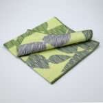Celebration design dinner napkin in green folded from hem and tassel