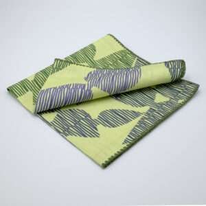 Celebration design dinner napkin in green folded from hem and tassel