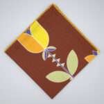 Lip TuLip design dinner napkin in orange flat folded from hem and tassel