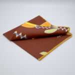 Lip TuLip design dinner napkin in orange folded from hem and tassel