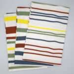 Not straight design set of three bold tea towels fanned out from hem and tassel