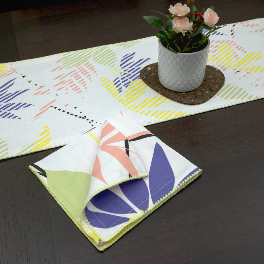 Pollen up design Dinner Napkin in yellow with pastels table runner looking down LS from hem and tassel
