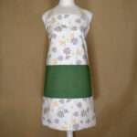 Shy dragonfly design apron with buff and grey flowers on mannequin from hem and tassel