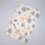Shy dragonfly flowers design tea towel in grey and buff flat folded from hem and tassel