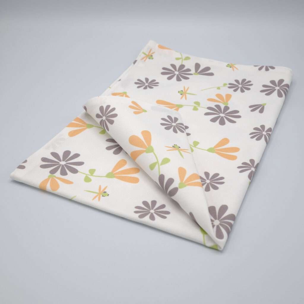 Shy dragonfly flowers design tea towel in grey and buff folded from hem and tassel