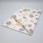 Shy dragonfly flowers design tea towel in grey and buff folded from hem and tassel