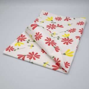 Shy dragonfly design tea towel in pink and yellow folded from hem and tassel