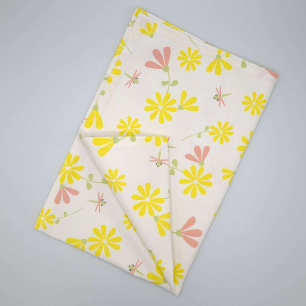 Shy dragonfly design tea towel in yellow and blush flat folded from hem and tassel