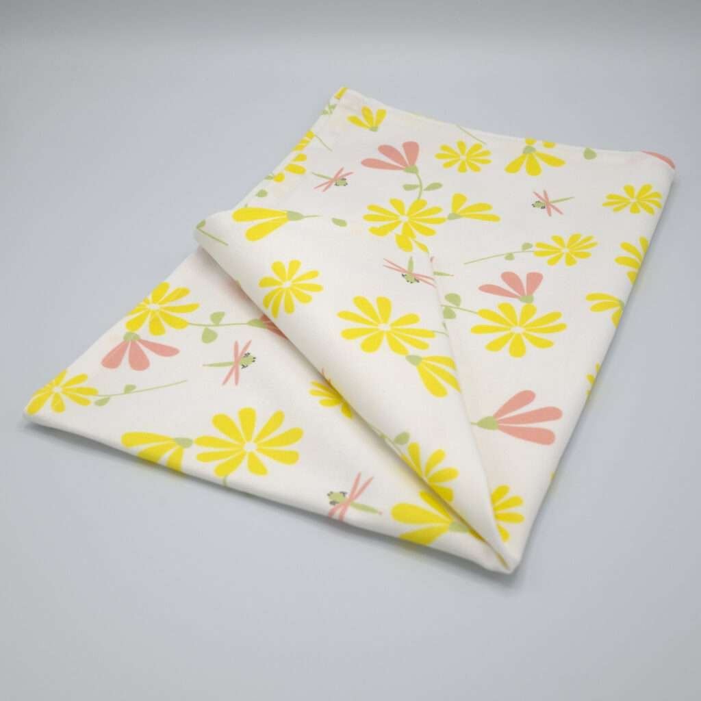Shy dragonfly design tea towel in yellow and blush folded from hem and tassel