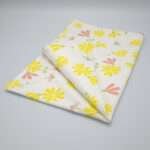 Shy dragonfly design tea towel in yellow and blush folded from hem and tassel