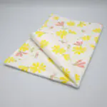 Shy dragonfly design tea towel in yellow and blush folded from hem and tassel