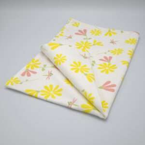 Shy dragonfly design tea towel in yellow and blush folded from hem and tassel