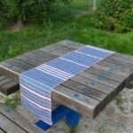 Table runner of rough stripes in blue design on picnic table by Hem And Tassel