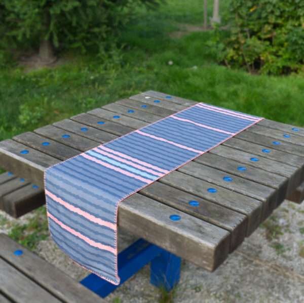 Table runner of rough stripes in blue design on picnic table by Hem And Tassel