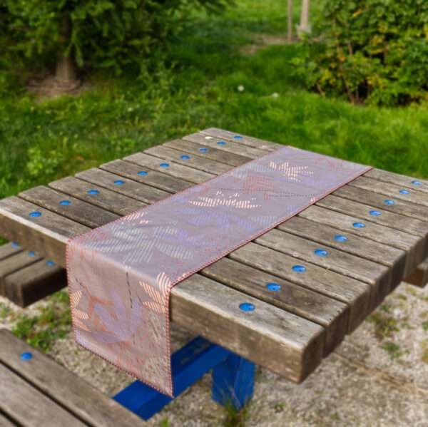 Table runner of pollen and flowers design in buff on picnic tabl By Hem And Tassel