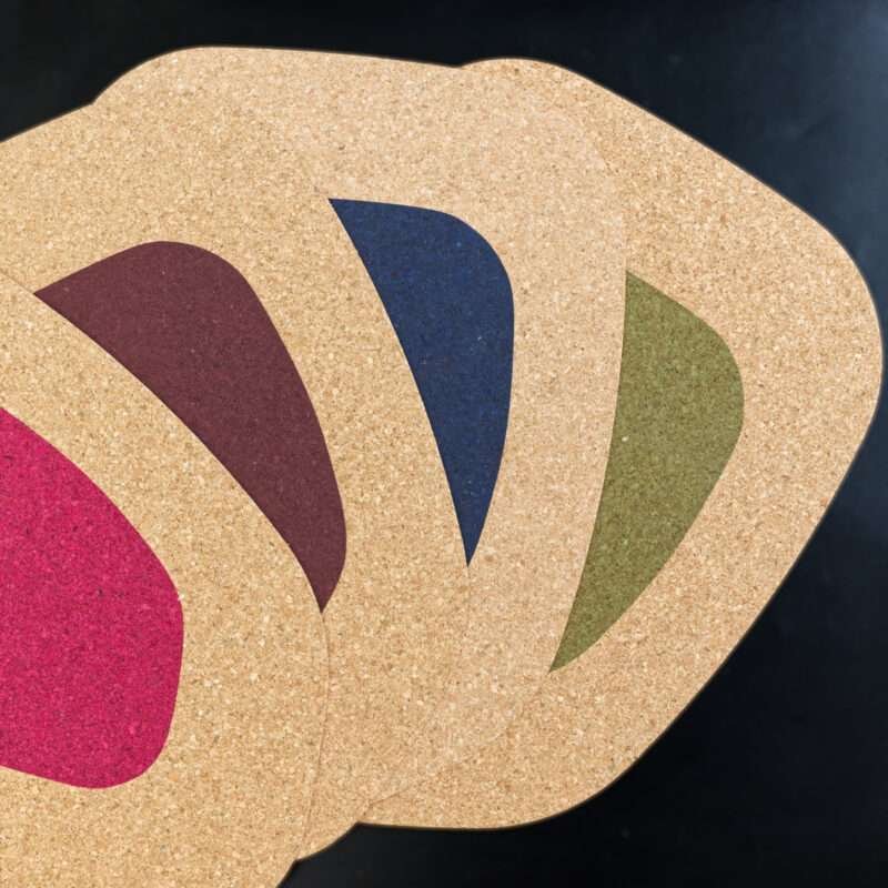 kidney bean cork placemats in four colors fanned out from top including wine, clay blue and green colors