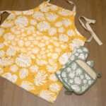 monster-ah design apron in orange with turf oven mitt and pot holder flat from hem and tassel