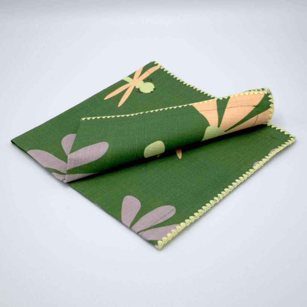 hiding shy dragonfly design dinner napkin in green folded from hem and tassel
