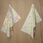 two hanging tea towels in blush and yellow from hem and tassel