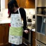Apron of Desert Haze cacti watercolor design on woman in kitchen by Hem and Tassel