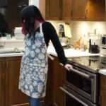 Apron of Monster Ah design on woman in kitchen by Hem and Tassel