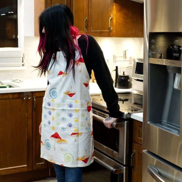 Apron of Magic mushroom design on woman in kitchen by Hem and Tassel
