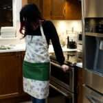 Apron of Shy Dragonfly Grey design on woman in kitchen by Hem and Tassel
