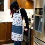 Apron of Shy Dragonfly Pink design on woman in kitchen by Hem and Tassel