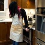 apron on woman in kitchen in symmetric squiggles design in buff by Hem And Tassel