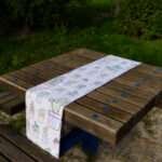Table runner of desert haze design with succulents print on picnic table in park by Hem And Tassel