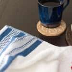 Houndstooth luxury white terry towel on table with coffee mug on cork coaster