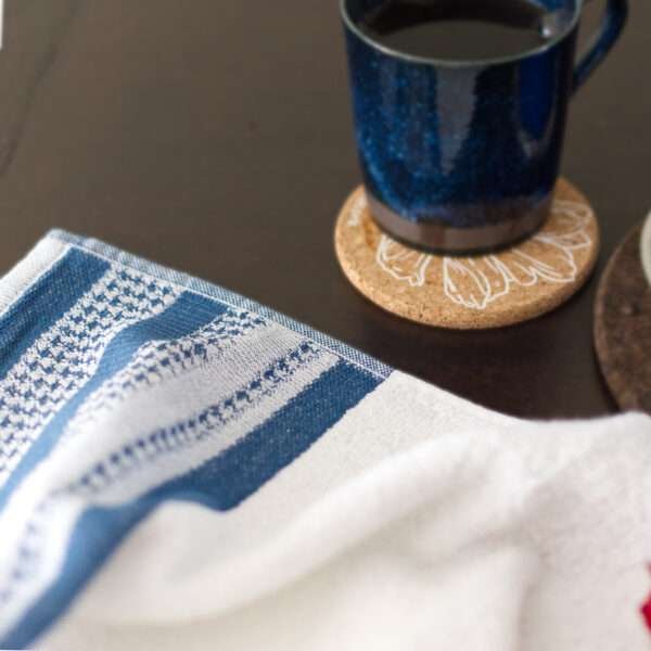 Houndstooth luxury white terry towel on table with coffee mug on cork coaster