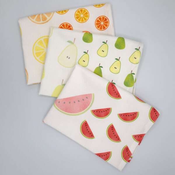 Faded fruit tea towels fanned out from hem and tassel
