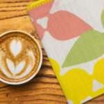 celebration design dinner napkin with cup of designer coffee on table from hem and tassel