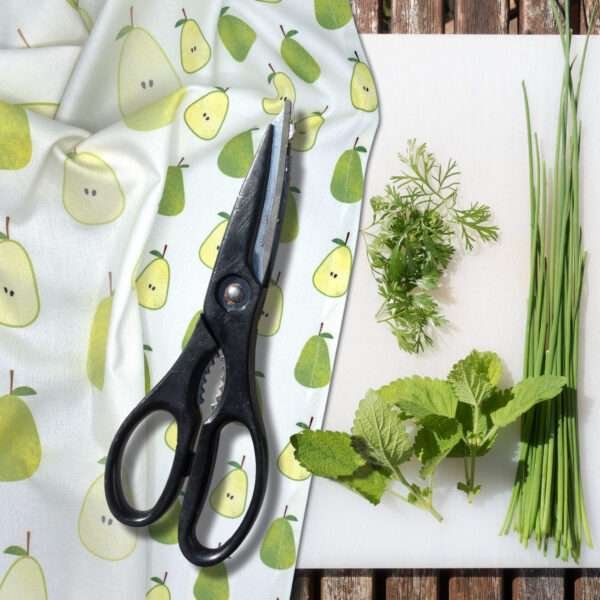 Faded pear design tea towel on chopping board with herbs from hem and tassel
