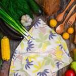 Pollen up tea towel yellow on counter with veggies by hem and tassel