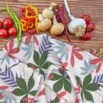 Pollen up tea towel pink on counter with veggies by hem and tassel