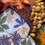 Pollen up tea towel buff on counter with veggies by hem and tassel