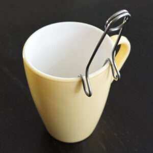 Clip style ball tea infuser resting on icon mug yellow by dte from hem and tassel