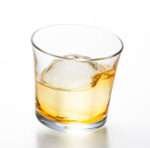 Tottering whiskey glass with drink and ice from hem and tassel