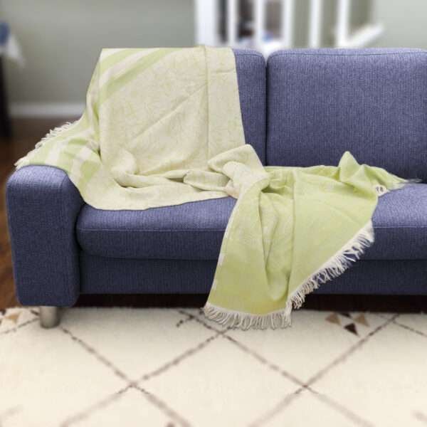 Pure cotton, jacquard throw in garden pattern in green on dark sofa by hem and tassel